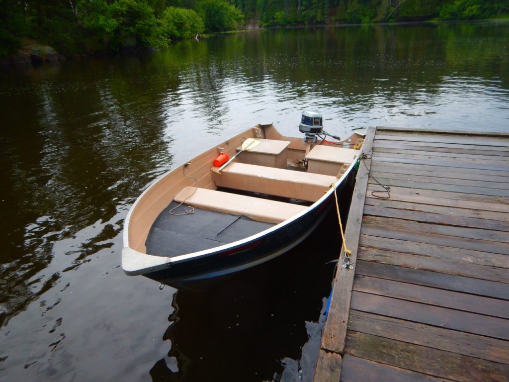 A boat with an outboard motor sitting on water docked