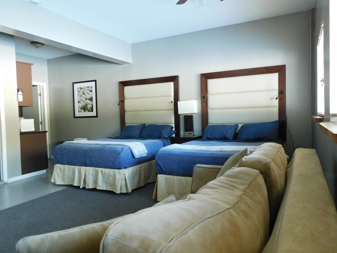View of a hotel room with two beds and a couch