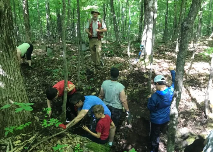A group of people in the woods working on collecting mineral specimens from the ground