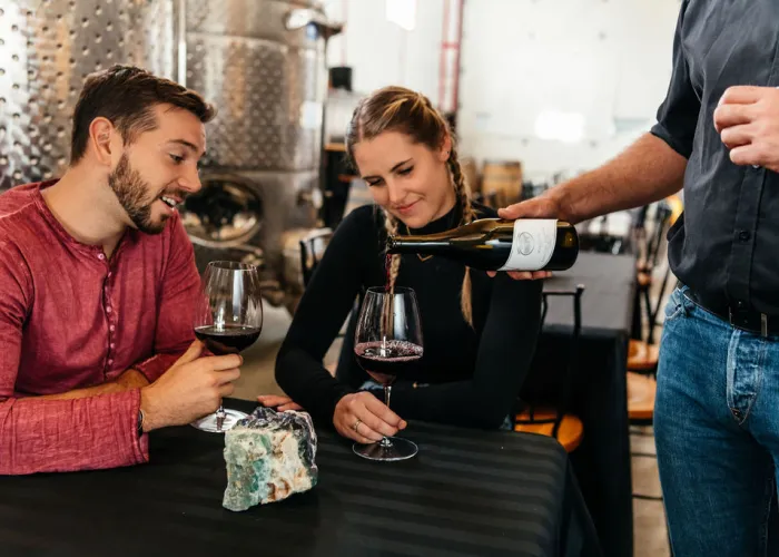 Two people at a table enjoying wine being served to them