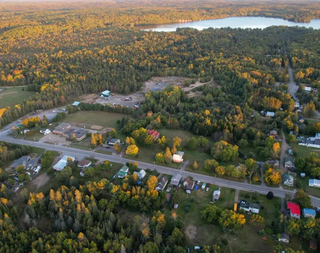 Aerial view of the hamlet of Coe Hill. With roads and houses surrounded by trees that are bright orange in the Fall.  