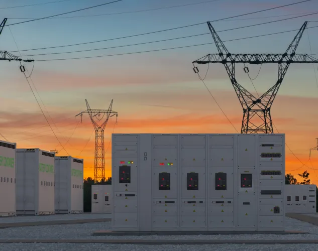 A battery storage unit for energy. A large rectangle white metal container, with power lines in the background.